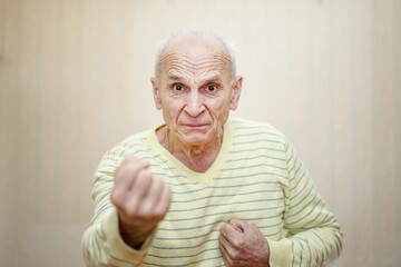 Gray haired angry senior man show hand with fist.