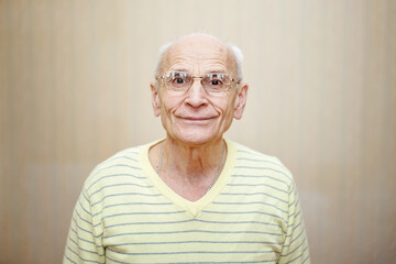 Elderly man with gray hair wearing eyeglasses looking with smile.