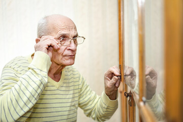 Senior male person in eyeglasses open wooden door of bookcase