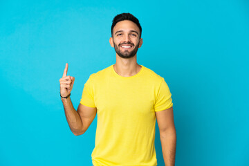 Young caucasian man isolated on blue background pointing up a great idea