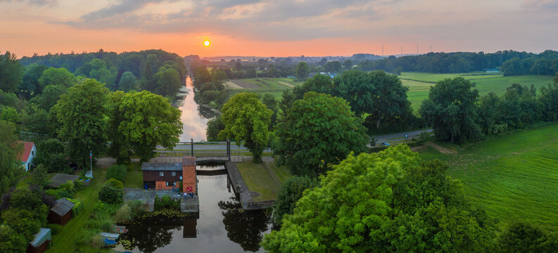 Summer sunset over river in countryside landscape. Lock at Kluvensiek of the Old Eider Canal, predecessor of the Kiel Canal. Eider River at Kluvensiek.