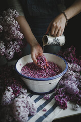 girl washes lilac flowers in a white basin