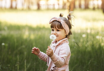 Little girl with white dandelion in the park in the summer