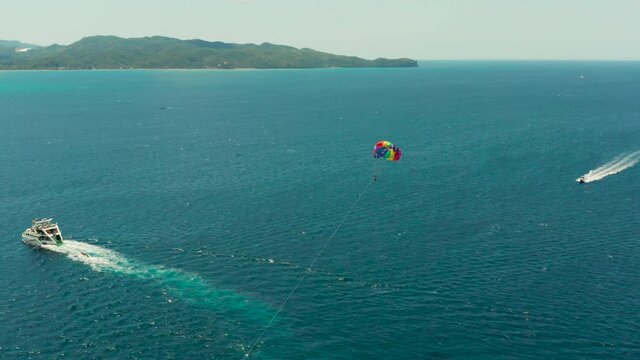 Tourists on a parachute over the sea, aerial view. Tourists parasailing on the Boracay, Philippines.