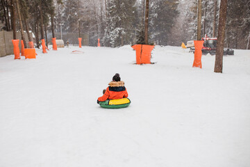 A child slides down a snowy slope on a tubing - winter holidays
