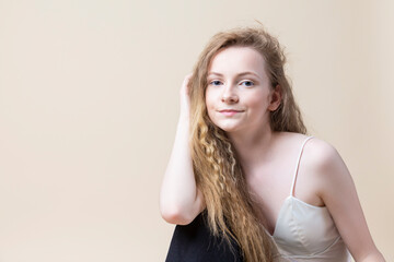 Smiling Caucasian Blond Girl In White Bra Sitting Over Beige Background.