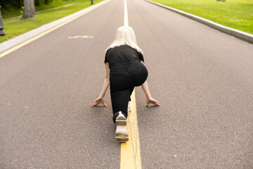 Athletic woman running in countryside road. Fitness female runner in ready start line pose outdoors in summer sprint challenge.