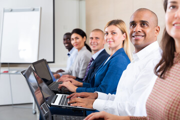 Obraz premium Side view of managers group working at laptops in company office