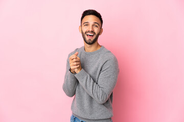 Young caucasian man isolated on pink background laughing