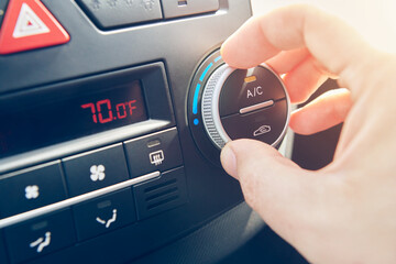 Man hand set the comfortable temperature in Fahrenheit of air conditioner in the car. Driver turning on car climate control system. Close up view with selective focus. - obrazy, fototapety, plakaty