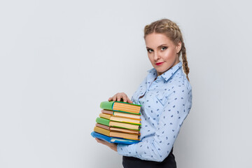 Education Concepts. Portrait of Caucasian Blond Female Posing With Heap of Books in Colorful Covers Against White.