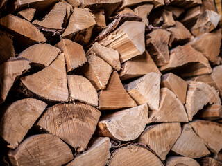 Fuel for stove heating. Rural life. Wooden firewood is stacked against the wall. Natural wood background. Free space for text.