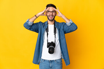 Young photographer girl isolated on yellow background with surprise expression