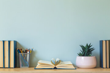 Home office desk table background. Empty wall with wooden table with stationery and books for work or study.