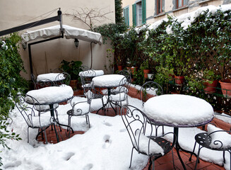 Tables and chairs covered in deep snow.