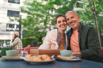 Happy woman with senior father looking at camera outdoors in city, back to normal concept.