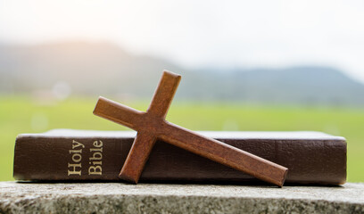 The cross and bible on stone with nature background.christian background