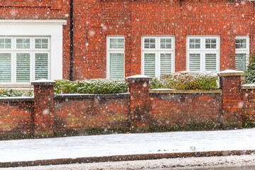 Heavy snow falling on London street in winter, causing icy and slippery pavement