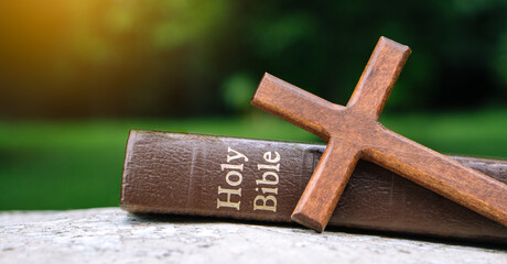The cross and bible on stone with nature background.christian background