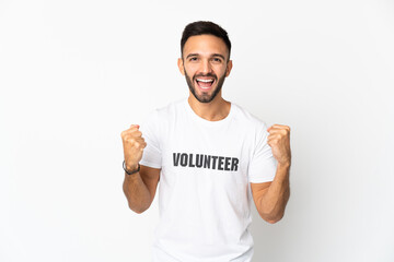Young caucasian volunteer man isolated on white background celebrating a victory in winner position
