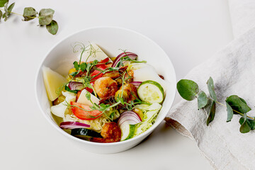 Delicious summer salad with fresh vegetables and seafood. Seasonal vegetables, shrimp and goat cheese. Healthy Mediterranean food. Food photography on a white background. Close-up