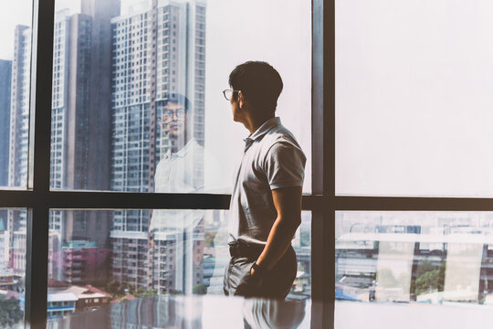 Side View Of A Man Standing Against Window In City