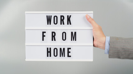 Hands is holding light box with word work from home on gray background.Wear grey suit.businessman concept.
