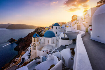 Beautiful sunset view to the idyllic village of Oia, Santorini island, Greece, with the blue domed churches on the edge of the volcanic caldera