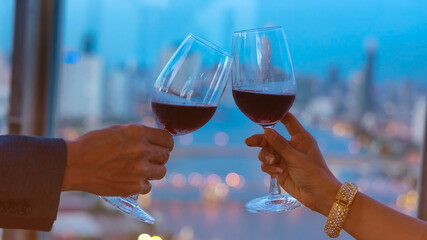 Selective focus of couple hand and wine glasses  which Happy Couple Toasting Glasses on a Summer Evening-rooftop city background