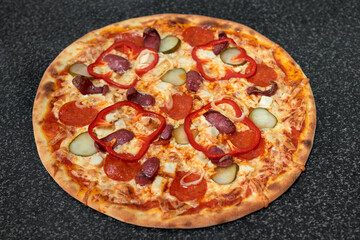 Delicious pizza with sausage, chicken, red pepper, pickles and onions