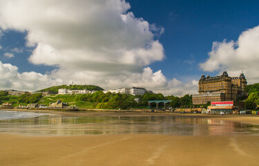 Low tide in the South Bay, Scarborough, North Yorkshire. The photo looks across the sands towards the Spa complex, Spa Bridge and Grand Hotel. - obrazy, fototapety, plakaty