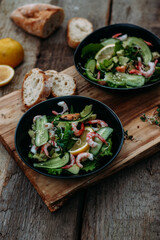 salad with seafood, avocado and herbs on a wooden background