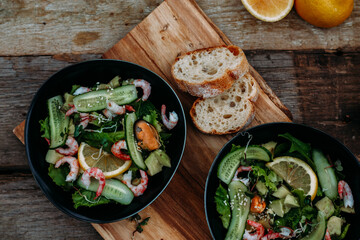 salad with seafood, avocado and herbs on a wooden background
