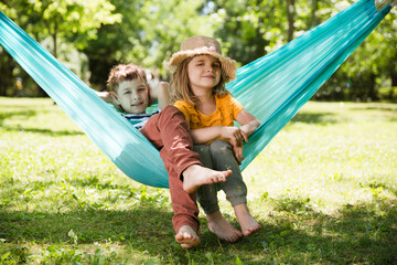 Two kids  swing in a hammock in a summer park or garden.