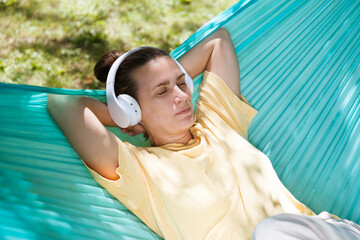 Audio healing. woman in headphones listens to audio recordings from the phone  lie in a hammock in...