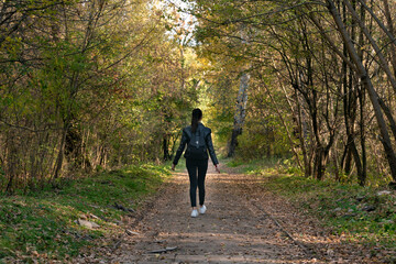 Obraz premium Lonely girl is walking in the alley of the park. Back view. Be in silence