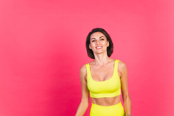 Obraz na płótnie Canvas Beautiful fit woman in yellow bright fitting sportswear on pink background happy moving excited perfect body fitness motivation