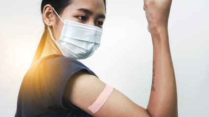Asian woman using adhesive bandage plaster on her arm after injection vaccine.