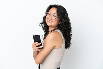 Fototapeta premium Young asian woman isolated on white background holding a mobile phone and with arms crossed