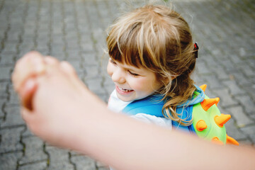 Mother accompanies preschool girl to daycare or school. Mom encourages student child to accompany her to school. Caring mother holds daughter hand as she goes to school. Happy positive girl.