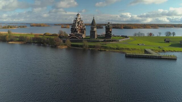 Helicopter forward to substantial Karelia Kizhi wooden church complex on island on lake Authentic historical no nails traditional tample travel unique Russia landmark. Romantic clouds. Golden ring