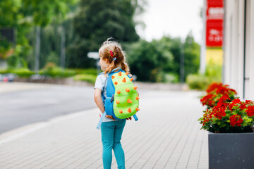 Cute little preschool girl going to playschool. Healthy toddler child walking to nursery and kindergarten. Happy child with backpack on city street, outdoors. City, traffic, safety on school way.