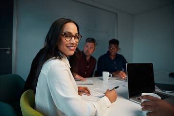 Portrait of young smiling female employee looking at camera while working at workplace