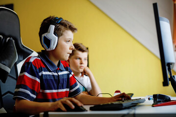 Two kids boys playing computer games on desktop pc. Modern addict activity for children. Siblings and friends gaming at home. - obrazy, fototapety, plakaty
