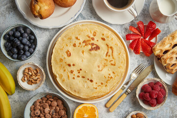 Breakfast table setting with fresh fruits, pancakes, coffee, croissants