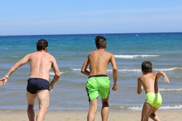 Tata i synowie podczas wygłupów na plaży. Dad and sons on the beach. - obrazy, fototapety, plakaty