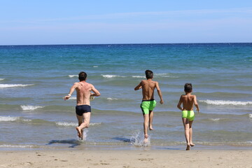 Fototapeta na wymiar Tata i synowie podczas wygłupów na plaży. Dad and sons on the beach.