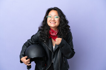 Fototapeta na wymiar Young asian woman with a motorcycle helmet isolated on purple background celebrating a victory in winner position