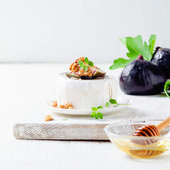 Brie cheese with fresh figs, honey and herbs on white background.