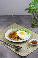 Nasi Goreng or Fried Rice, one of Indonesian popular food, topping with sunny side up egg, cucumber slices, lettuce and crackers. Top view, copy space for text.